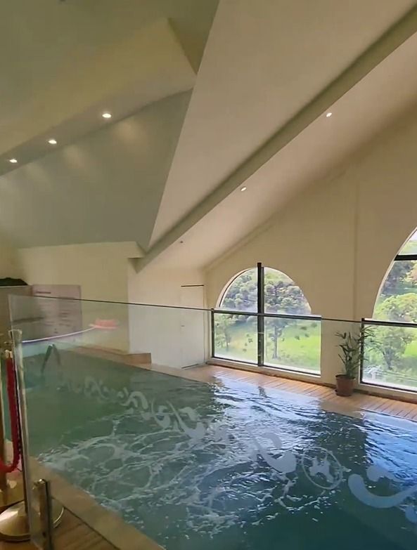Uma grande piscina coberta com cerca de vidro e muitas janelas.
