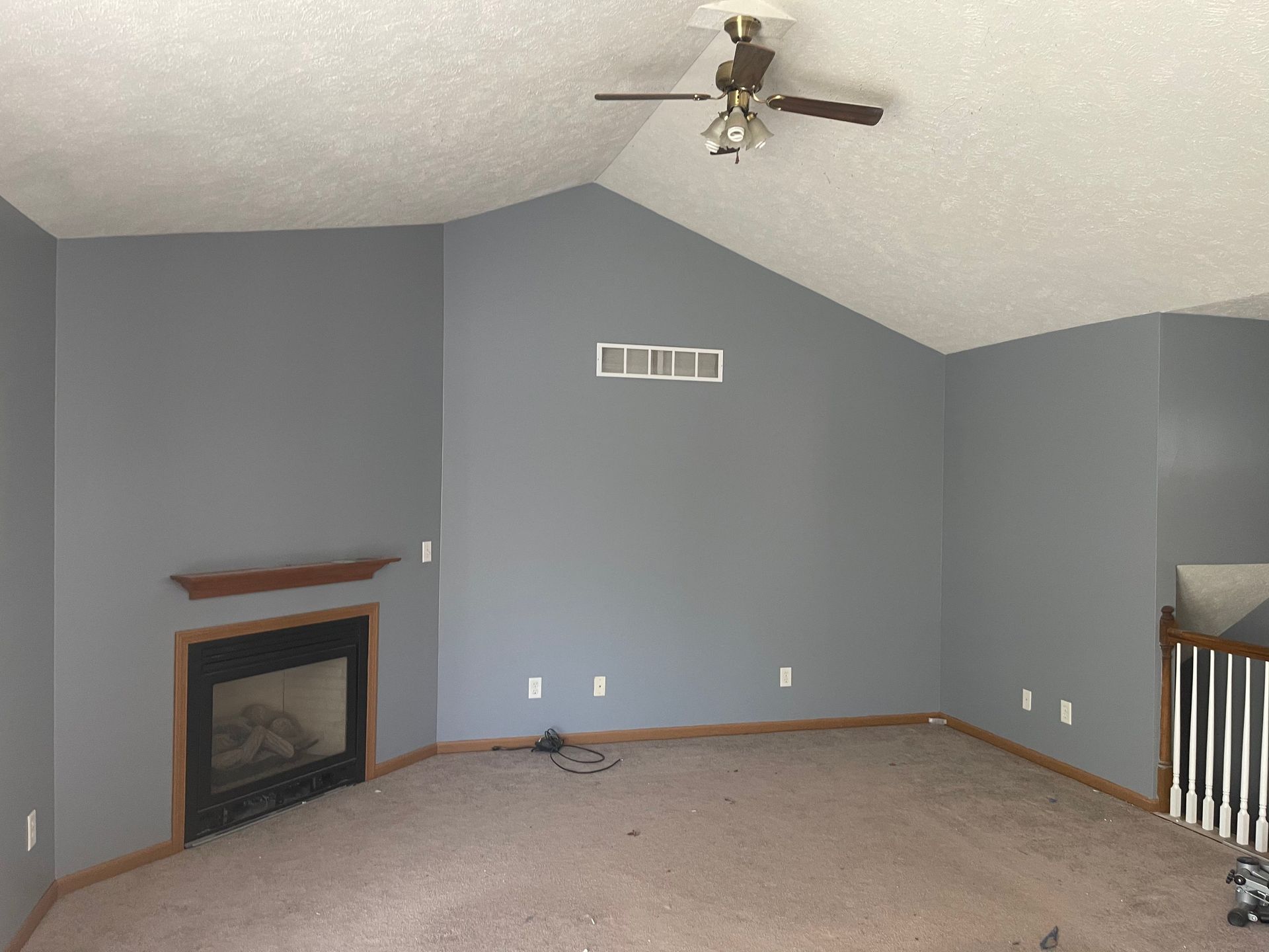 An empty living room with a fireplace and ceiling fan
