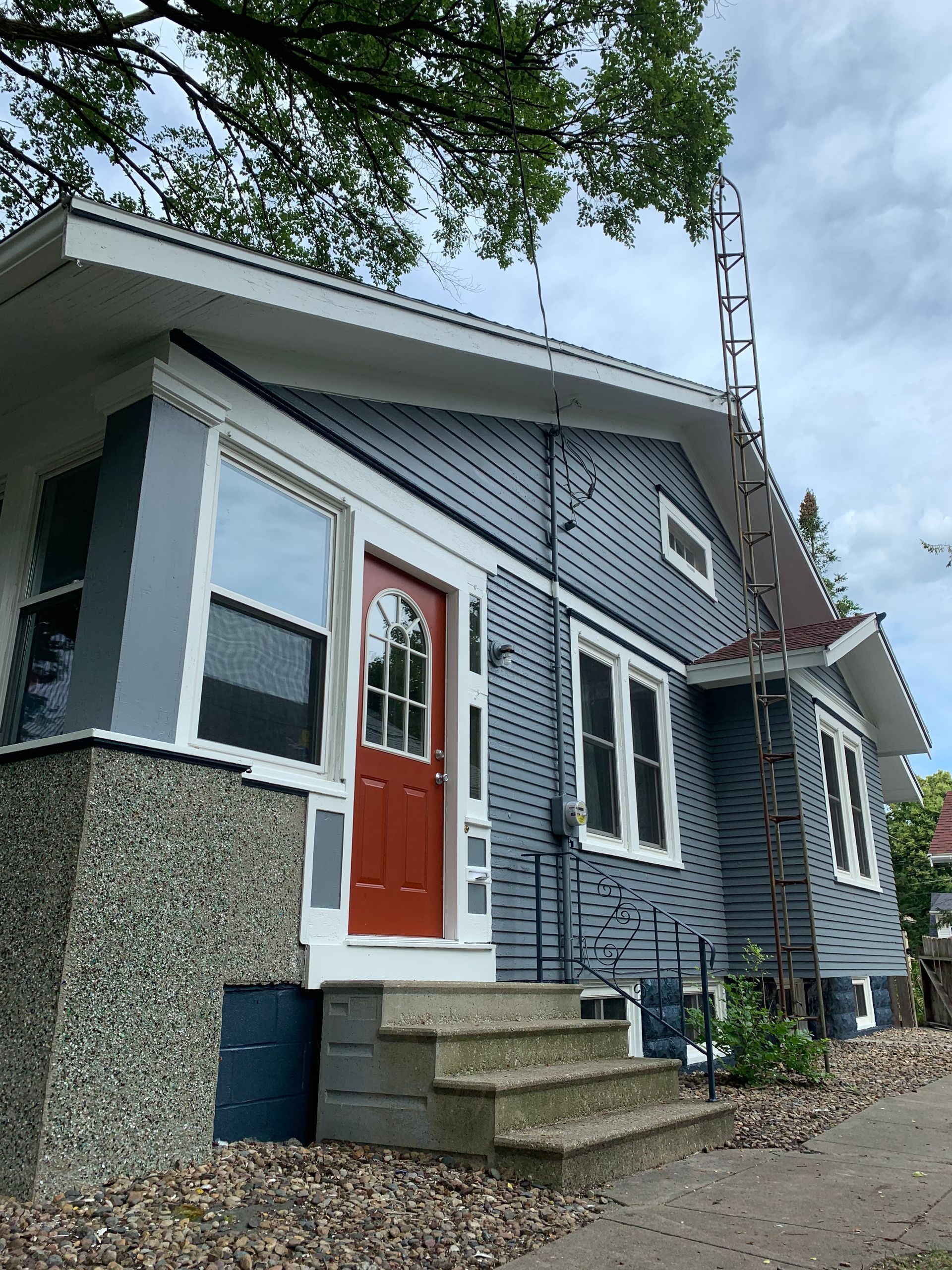 A blue house with a red door and stairs
