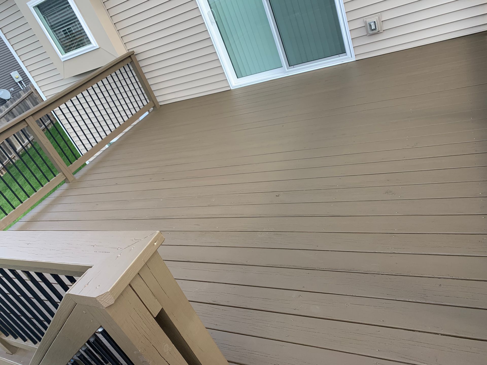 A deck with a sliding glass door and a railing.