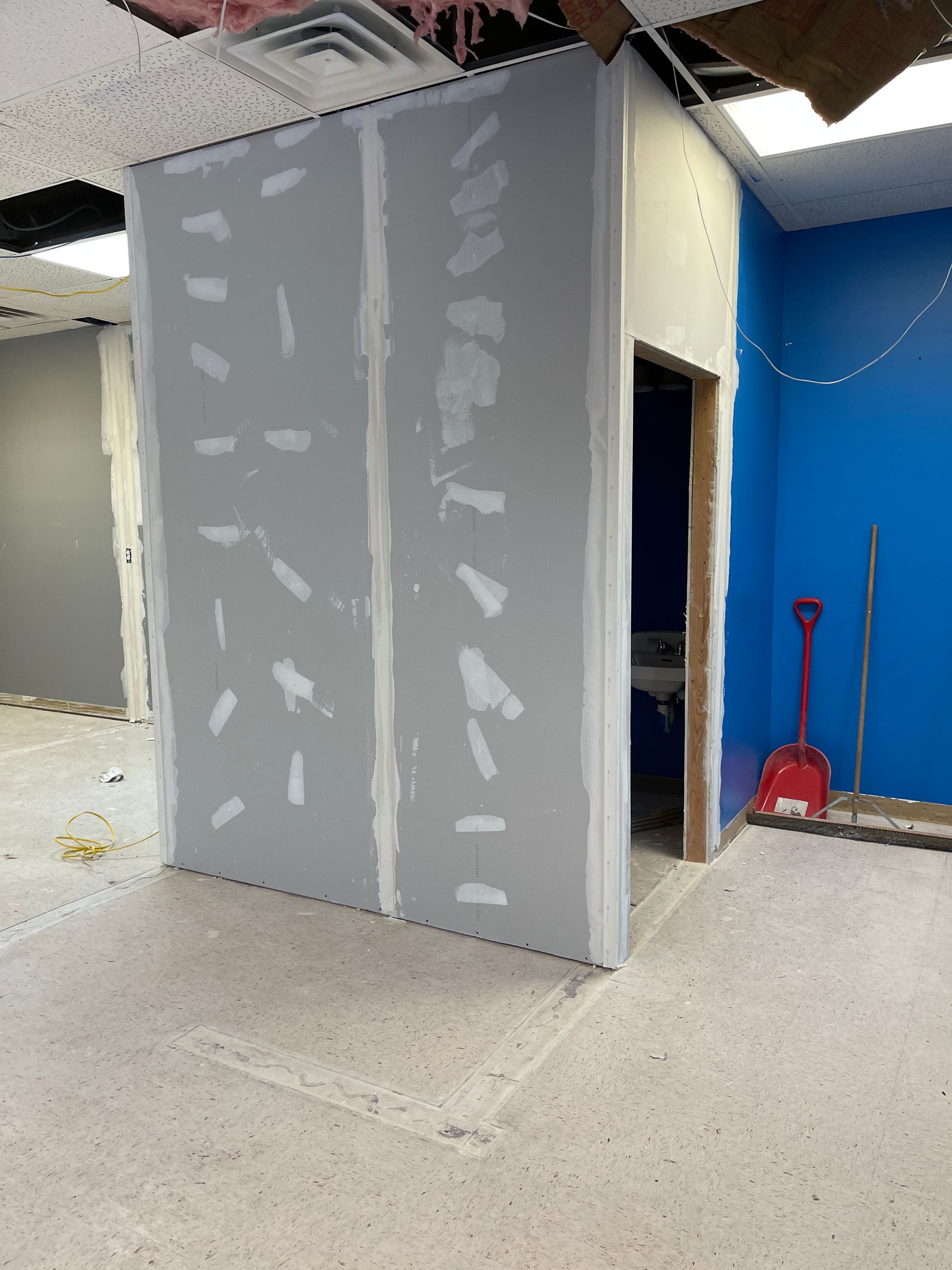 An empty room with a blue wall and a red shovel.