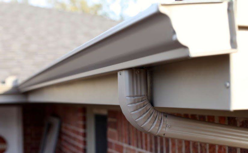 A close up of a gutter on the side of a brick house.