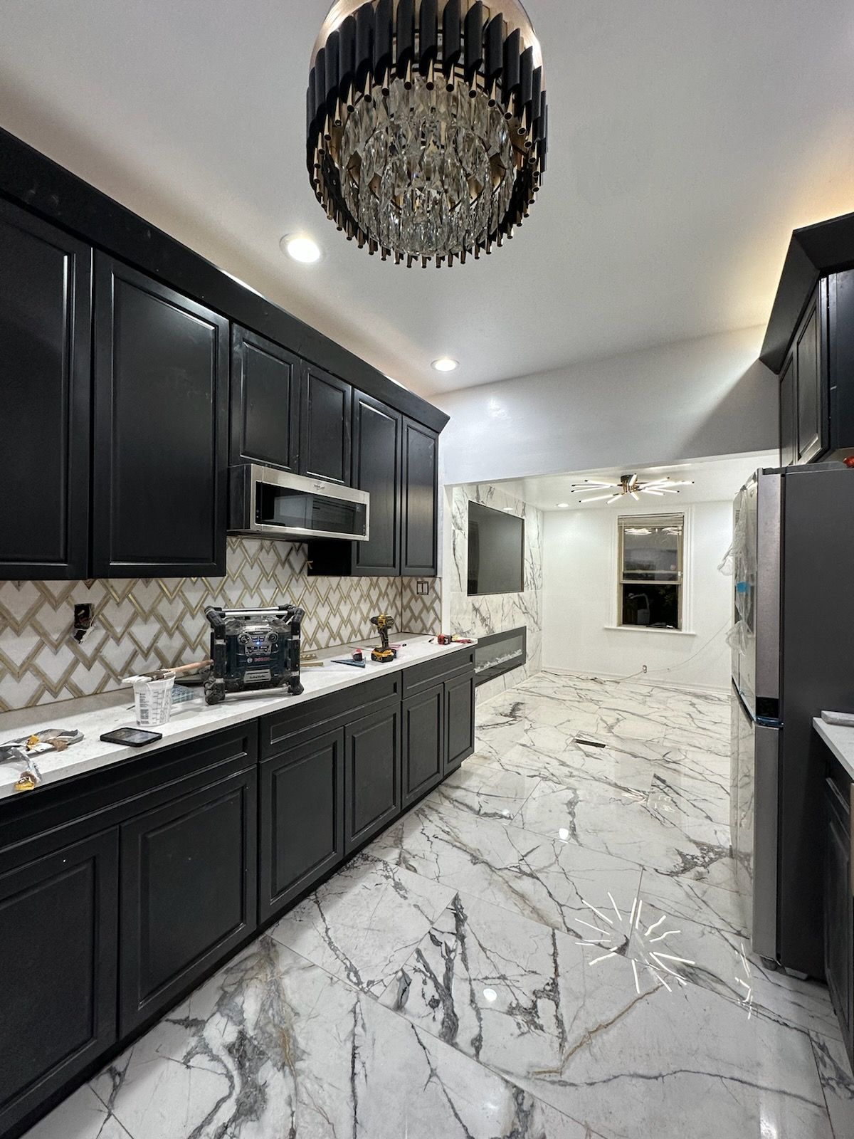 A kitchen with white cabinets , stainless steel appliances , wooden floors and a large island with chairs.