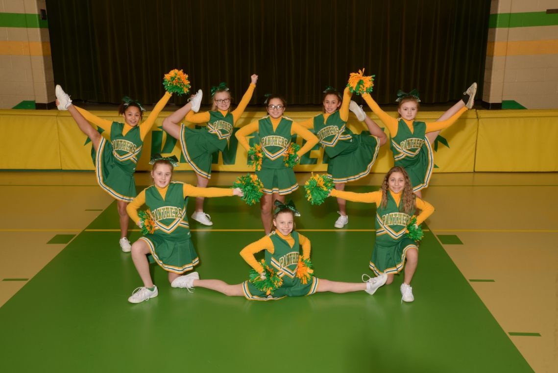 A group of cheerleaders wearing green and yellow uniforms with the word eagles on them