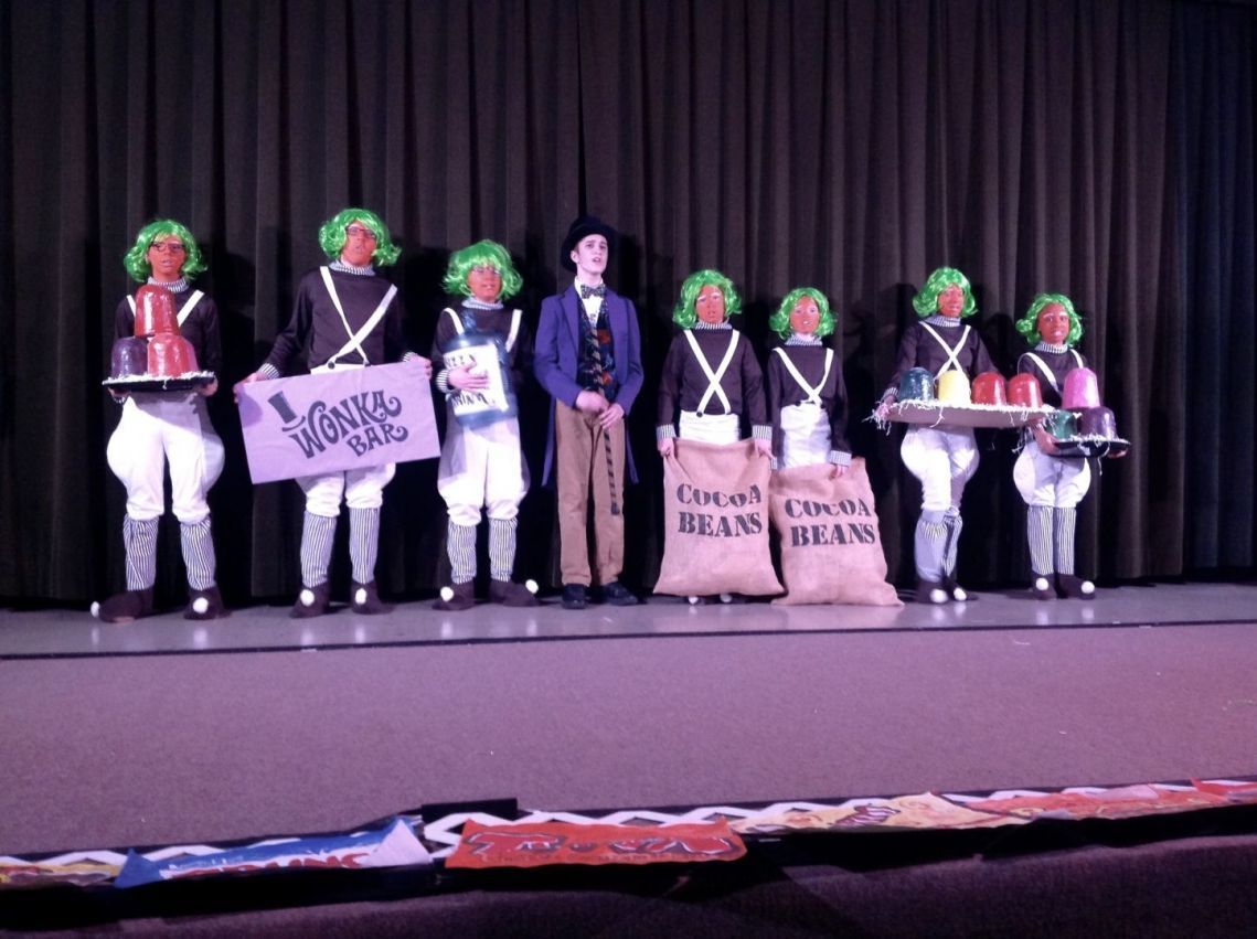 A group of people standing on a stage holding trays of chocolate beans