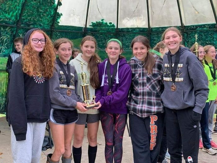A group of young girls are posing for a picture while holding a trophy.
