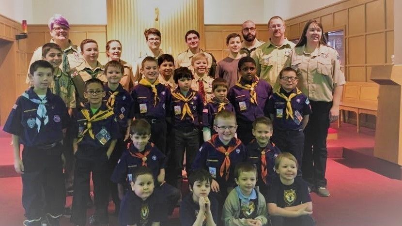 A group of boy scouts are posing for a picture in a church.