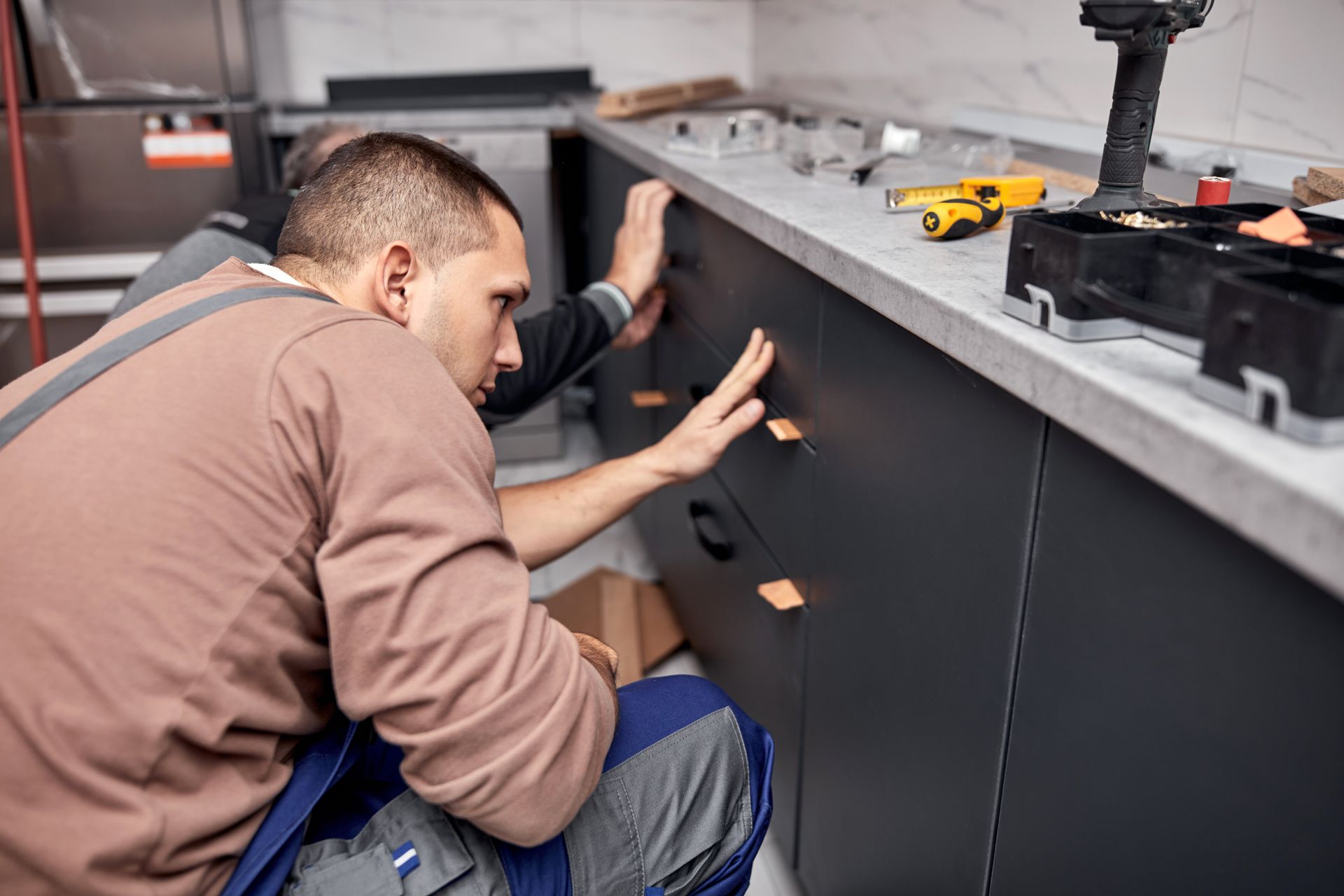 Two workers working on cabinets