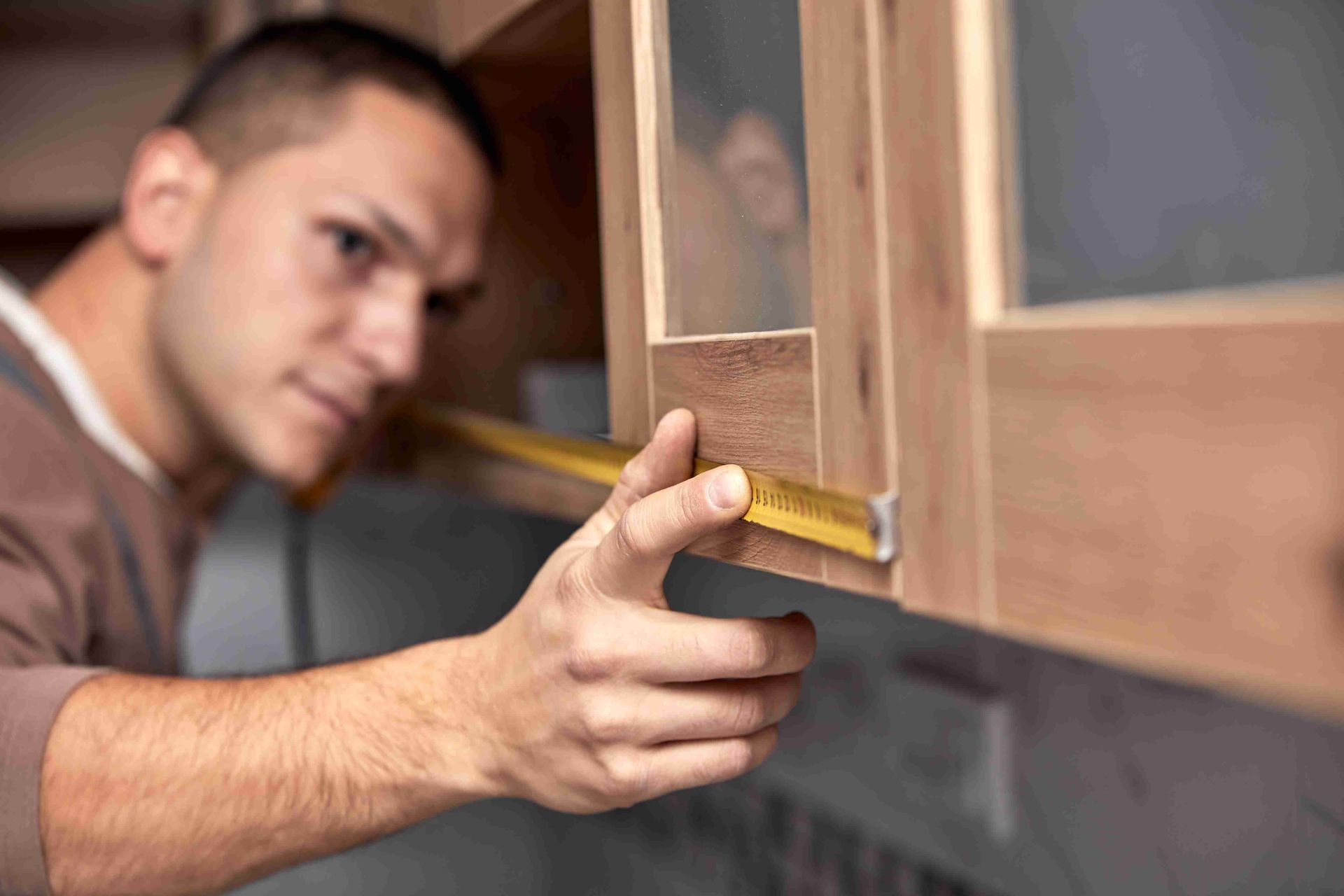 A man measuring cabinets for refacing