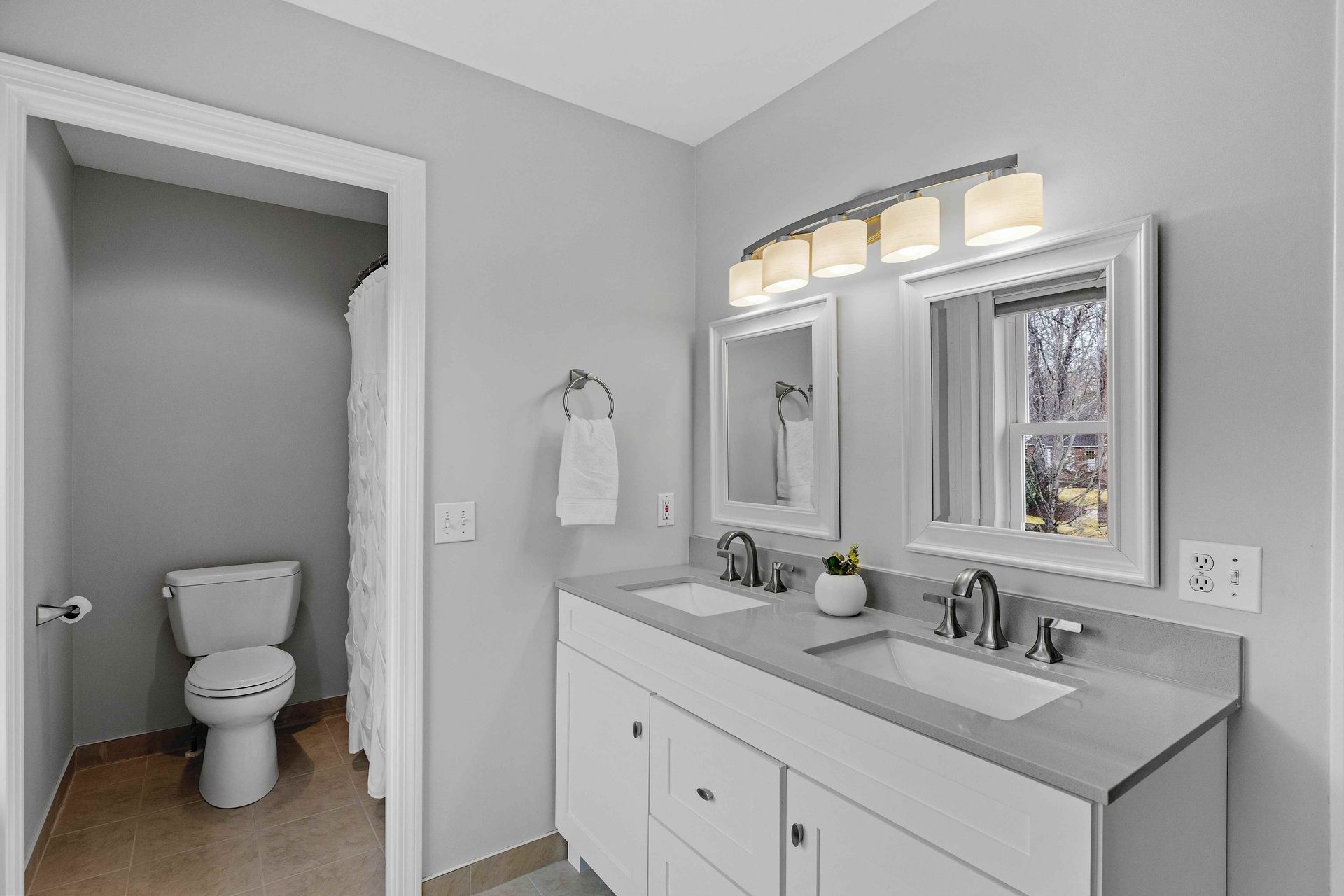 A white bathroom vanity with a grey counter on top with a double sink