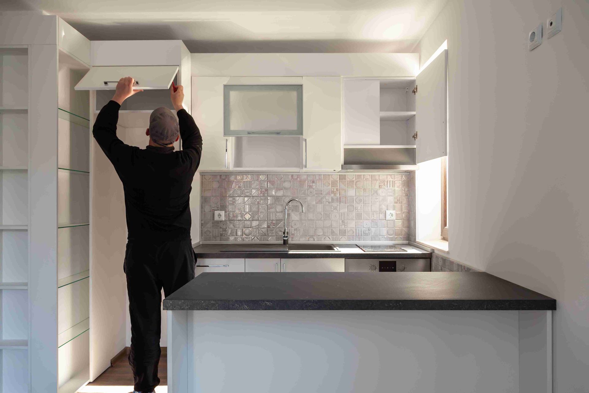 A man installing cabinetry in a kitchen