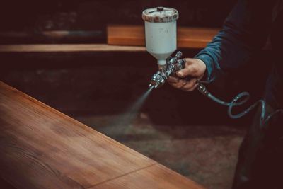 A man spraying a piece of wood with stain
