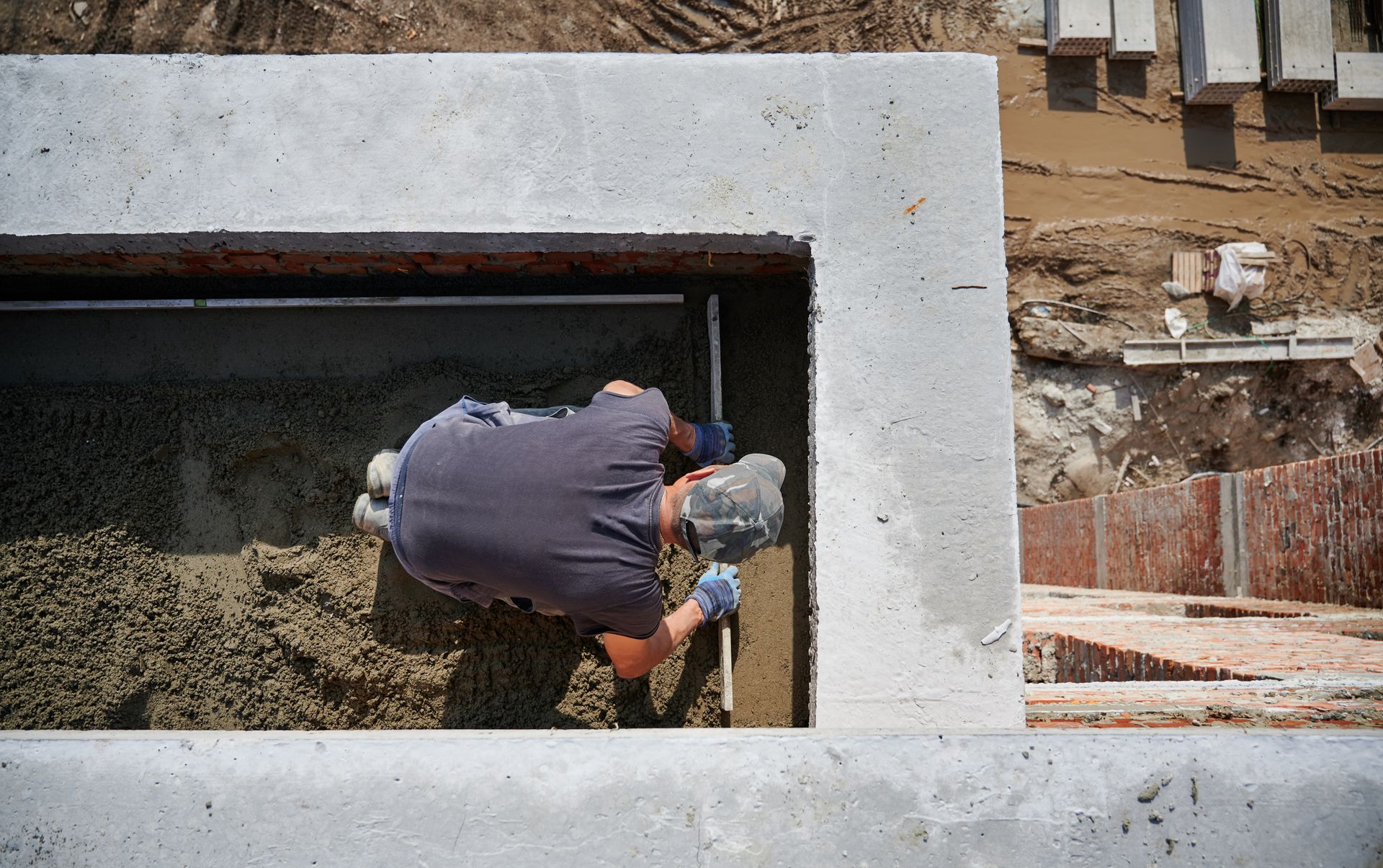 Construction worker smoothing cement in a concrete form, outdoors.