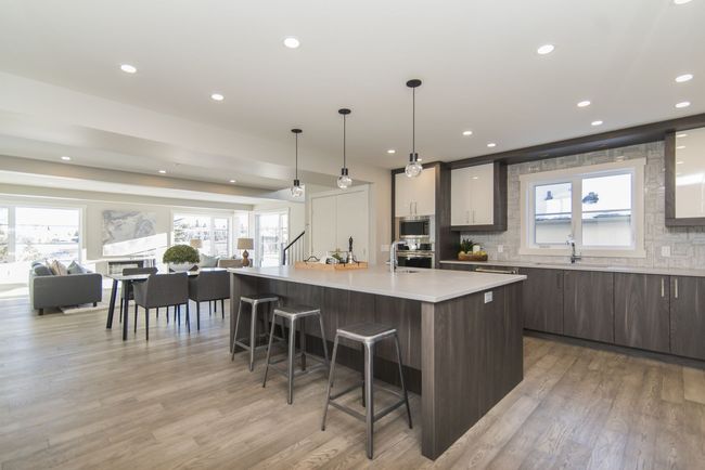 Modern kitchen with gray cabinetry, island with stools, and open dining area.