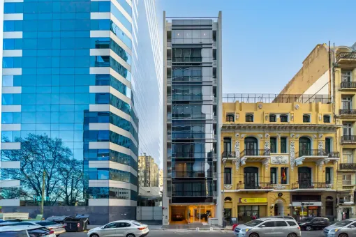 Un edificio con muchas ventanas está al lado de un edificio con muchas ventanas.