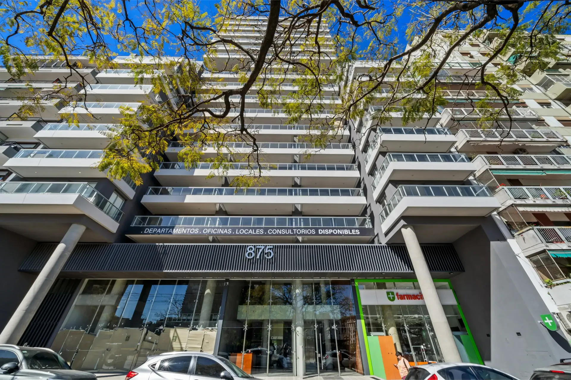 Un edificio alto con coches aparcados delante.