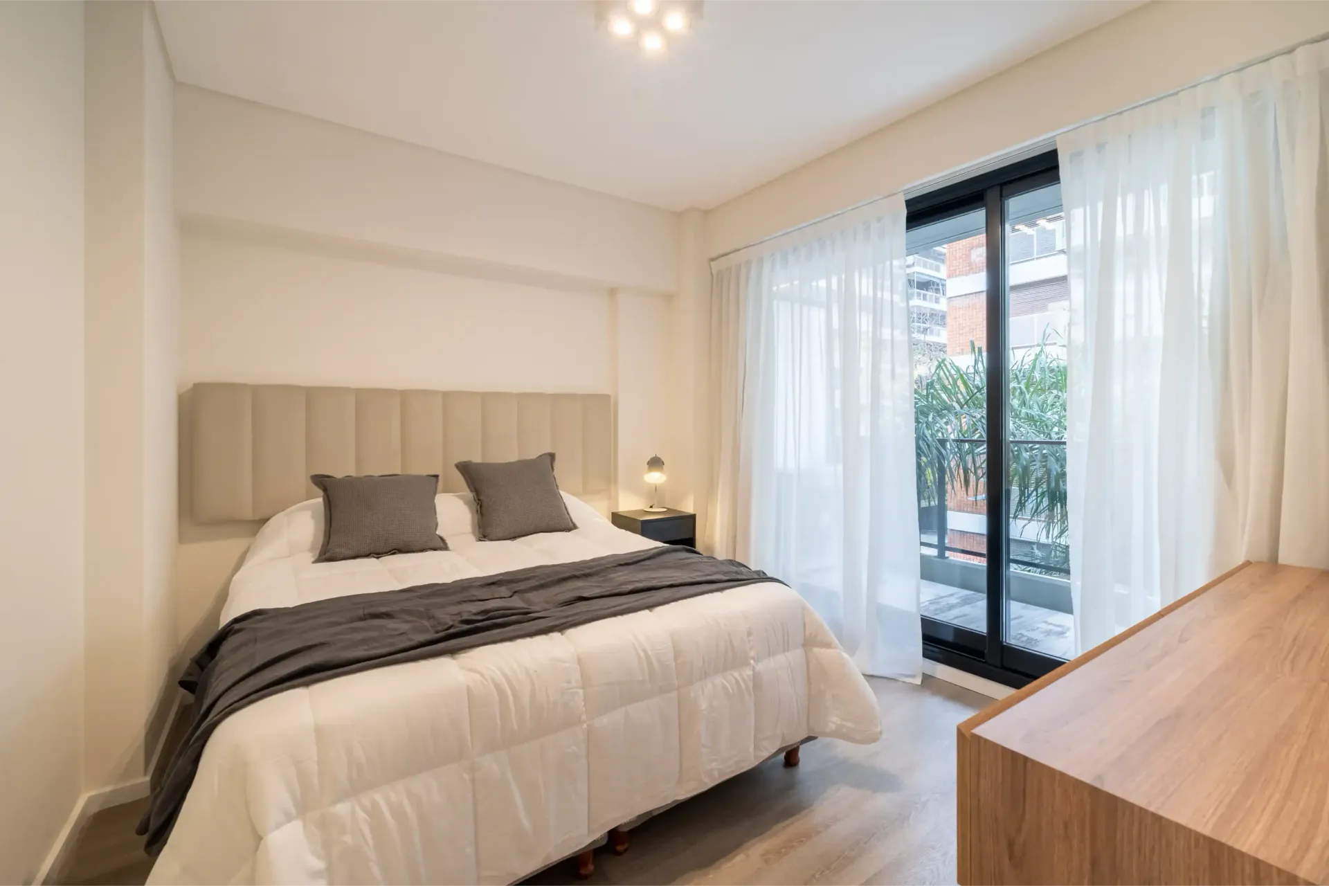 Un dormitorio con cama, tocador y puertas corredizas de vidrio.