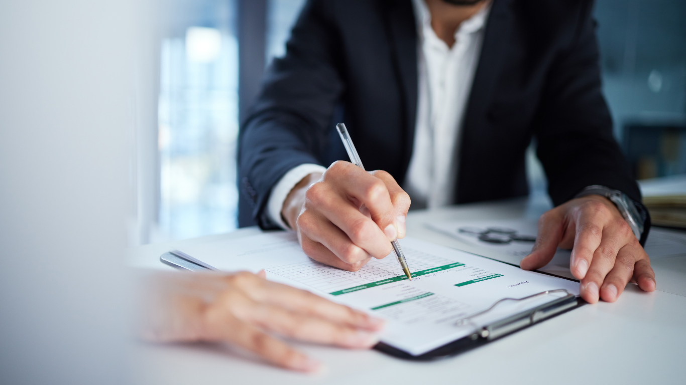 A man is sitting at a desk counting money