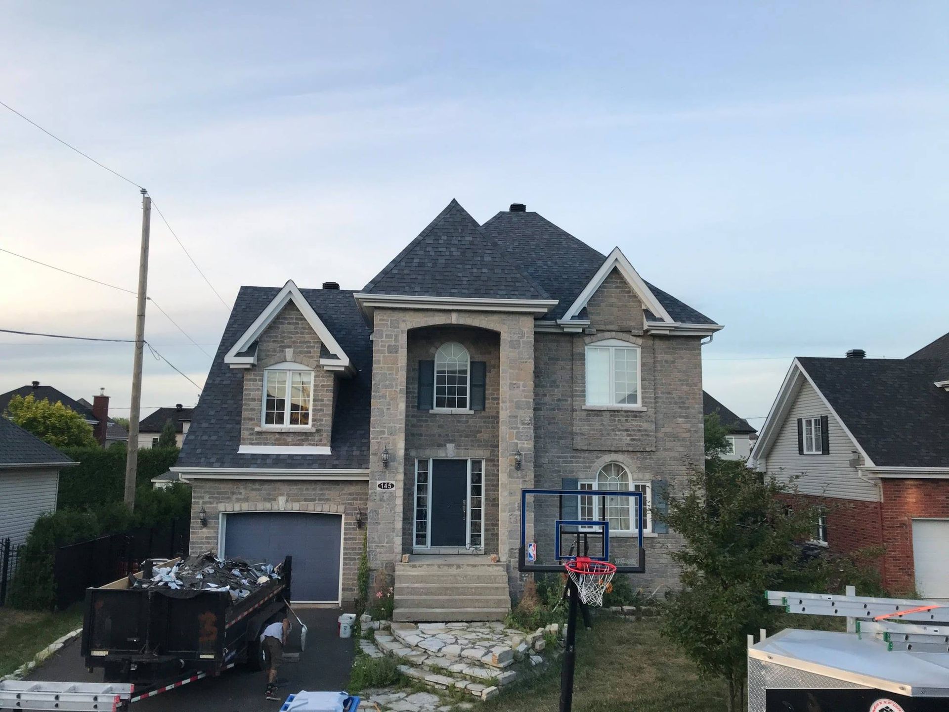 Une grande maison avec un panier de basket devant.