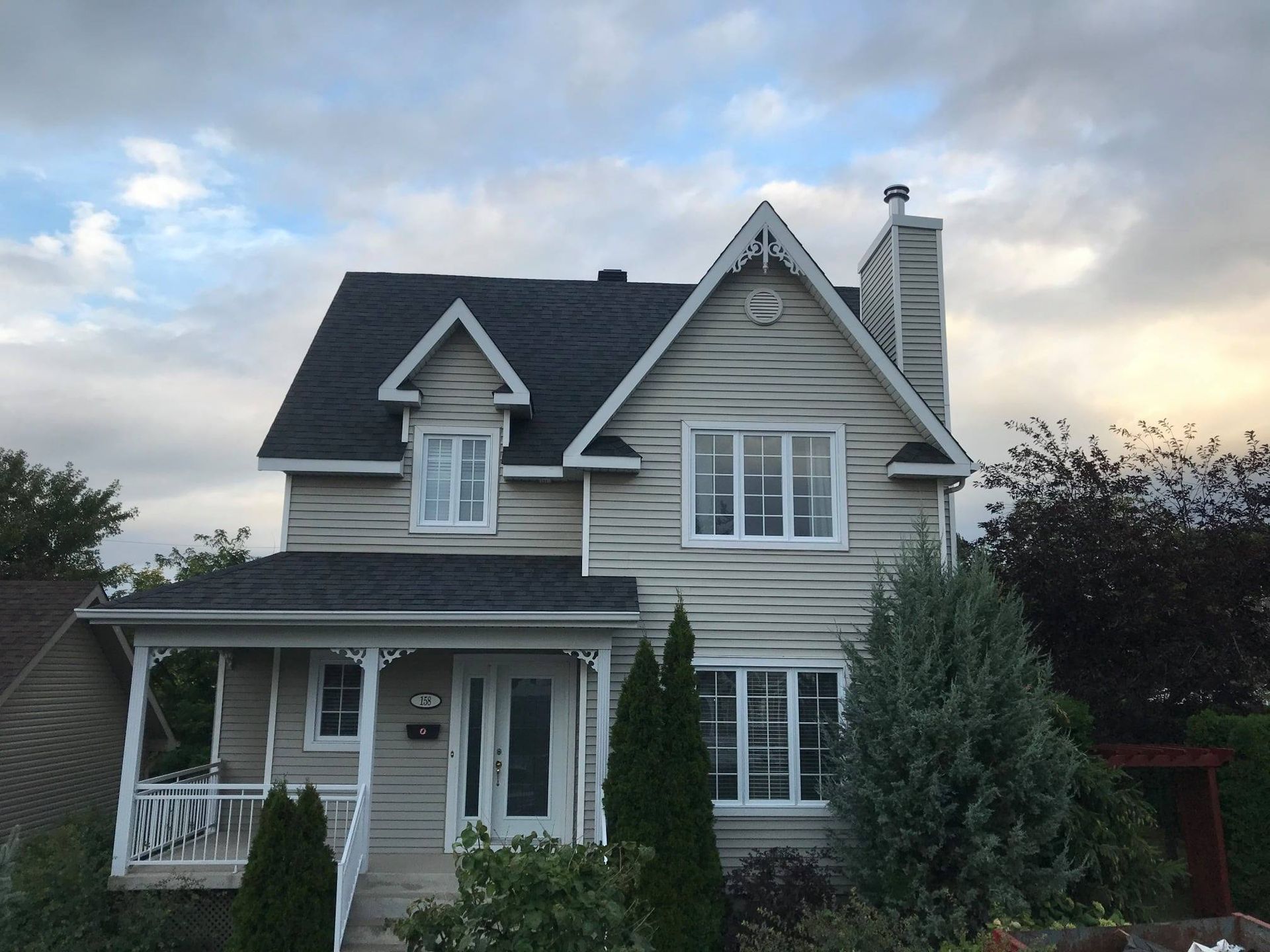 Une maison blanche avec un toit noir et un porche