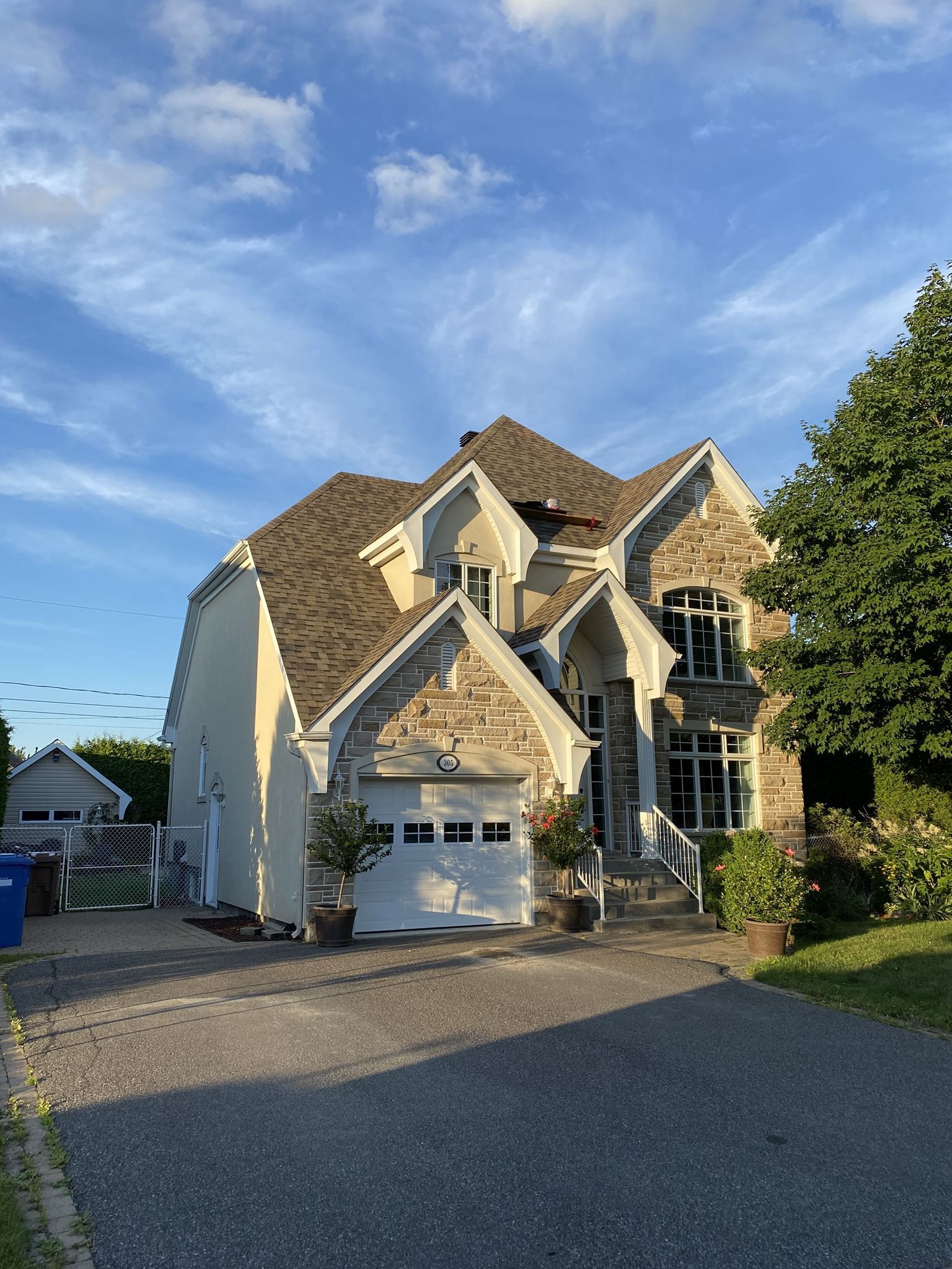 Une grande maison blanche avec un toit marron et une porte de garage blanche.