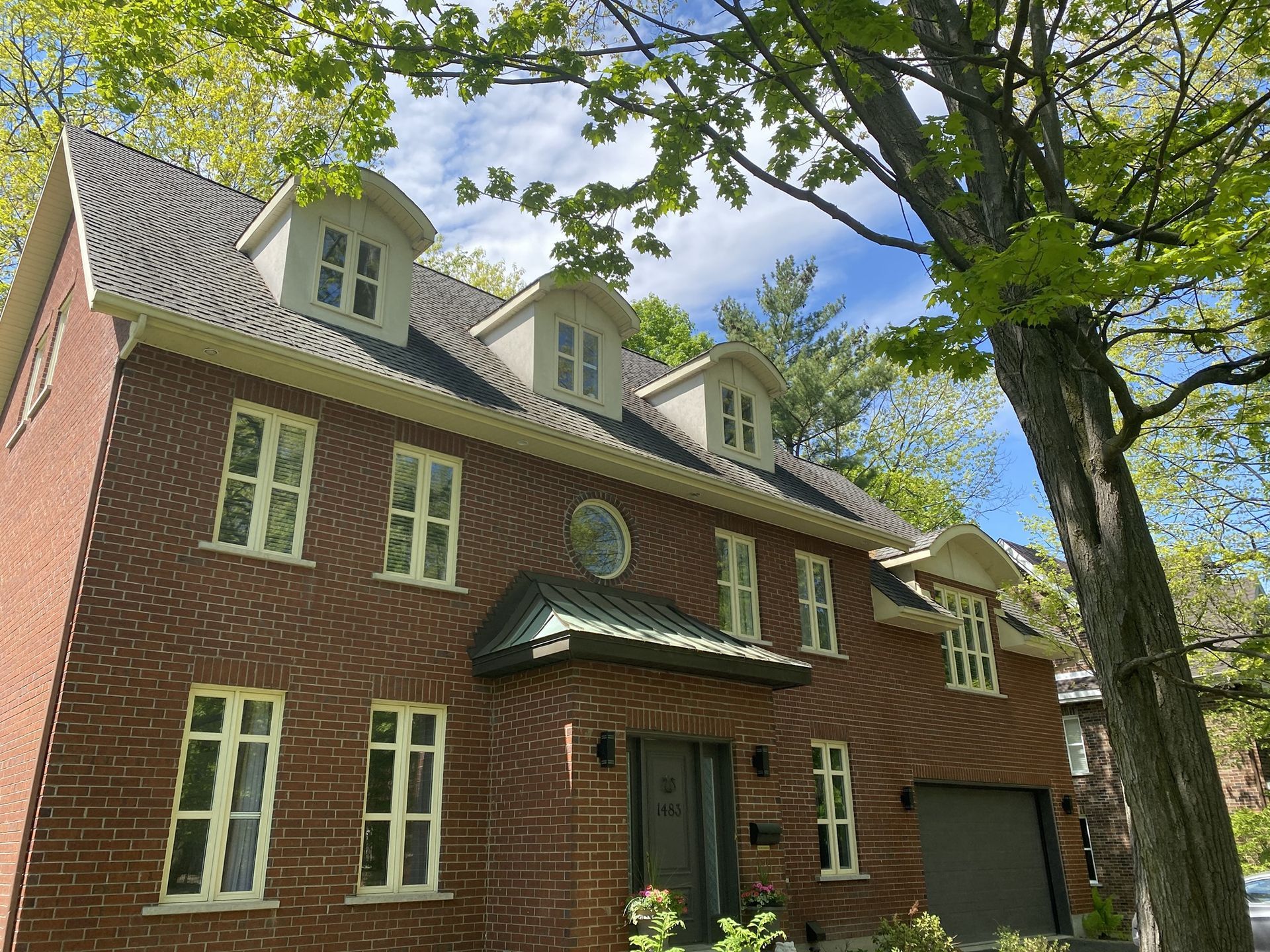 Une grande maison en briques avec un arbre devant.