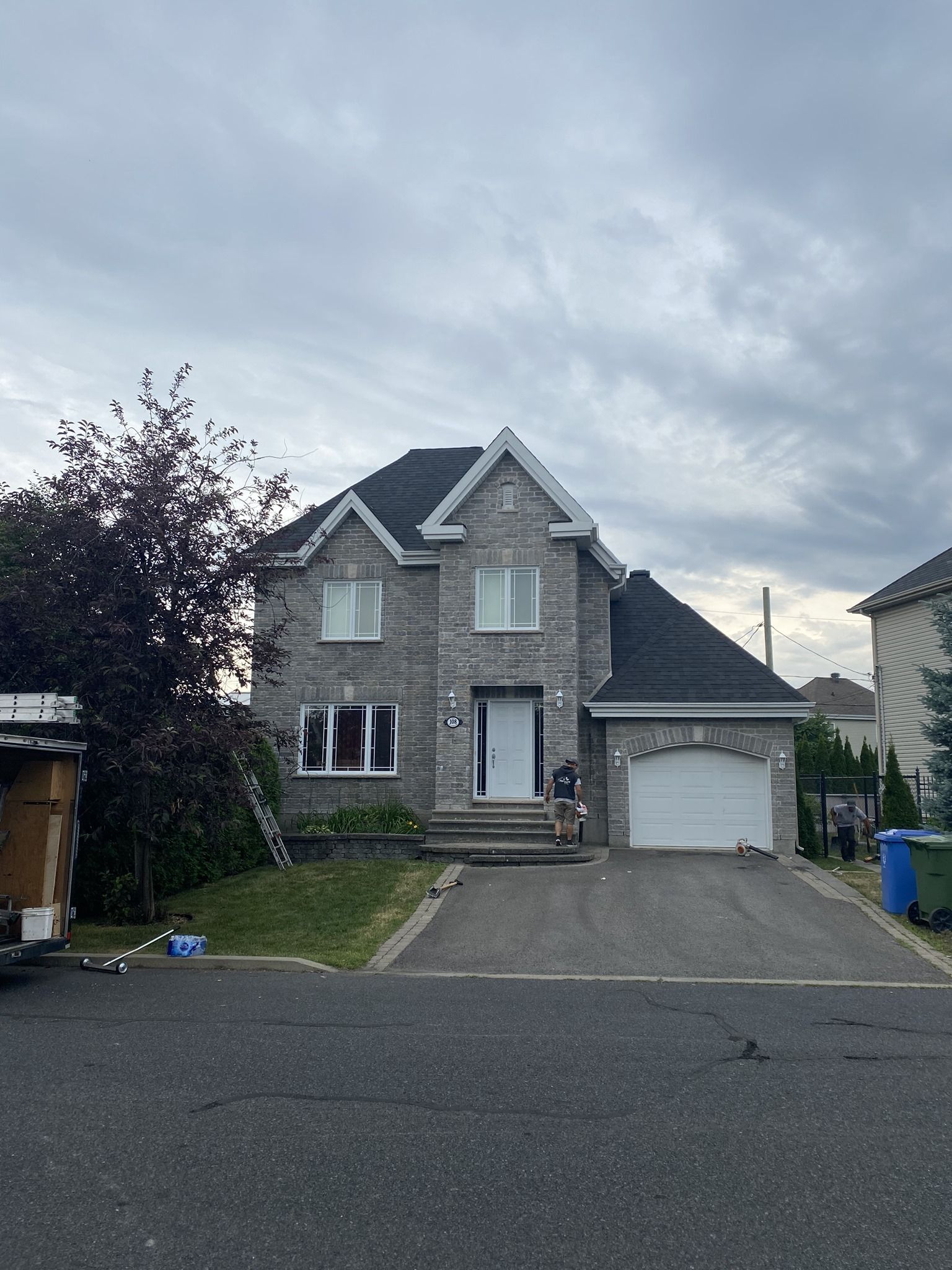 Une grande maison en briques avec un toit noir et une porte de garage blanche