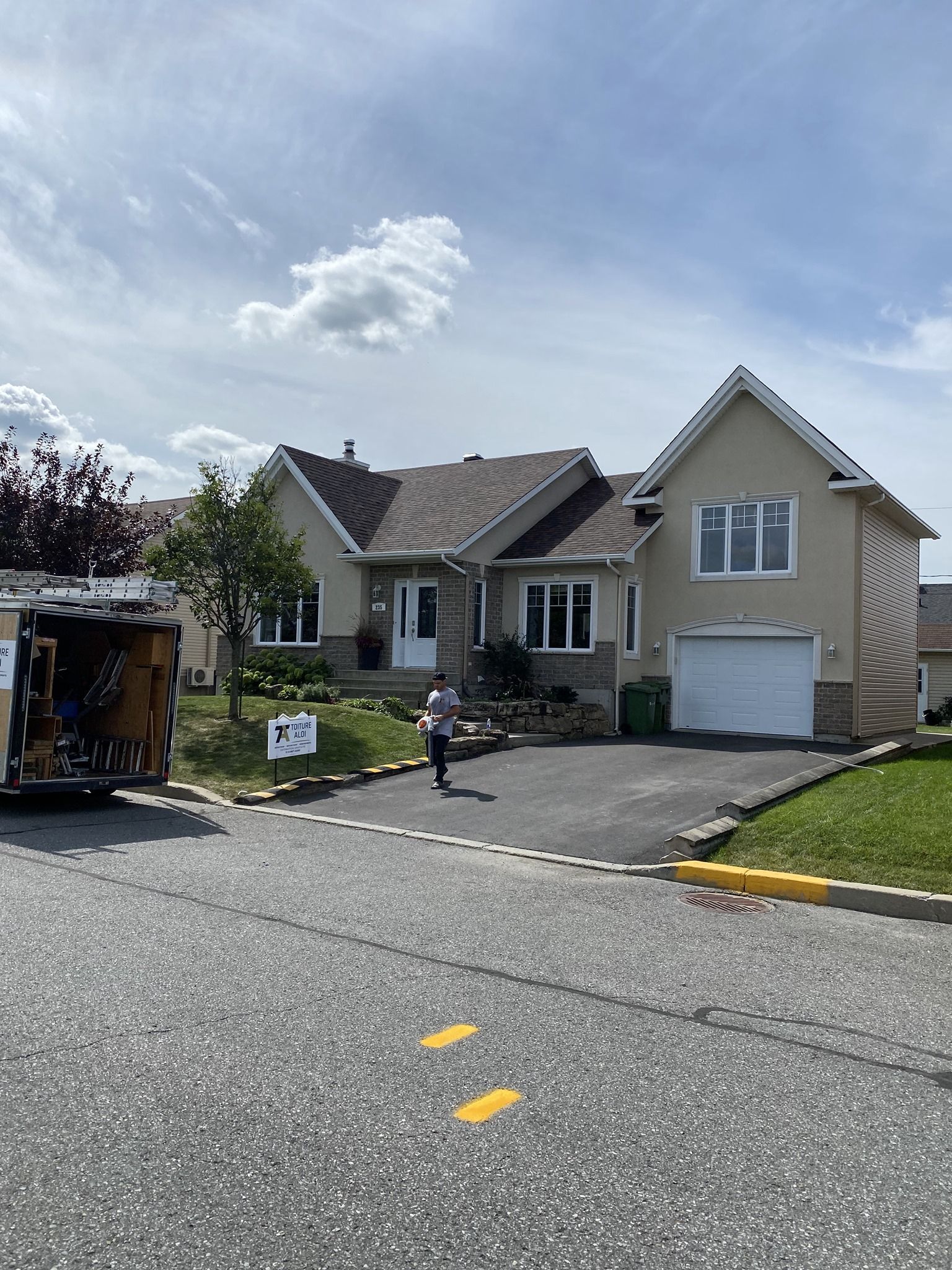 Un homme se tient devant une maison avec un camion garé devant.