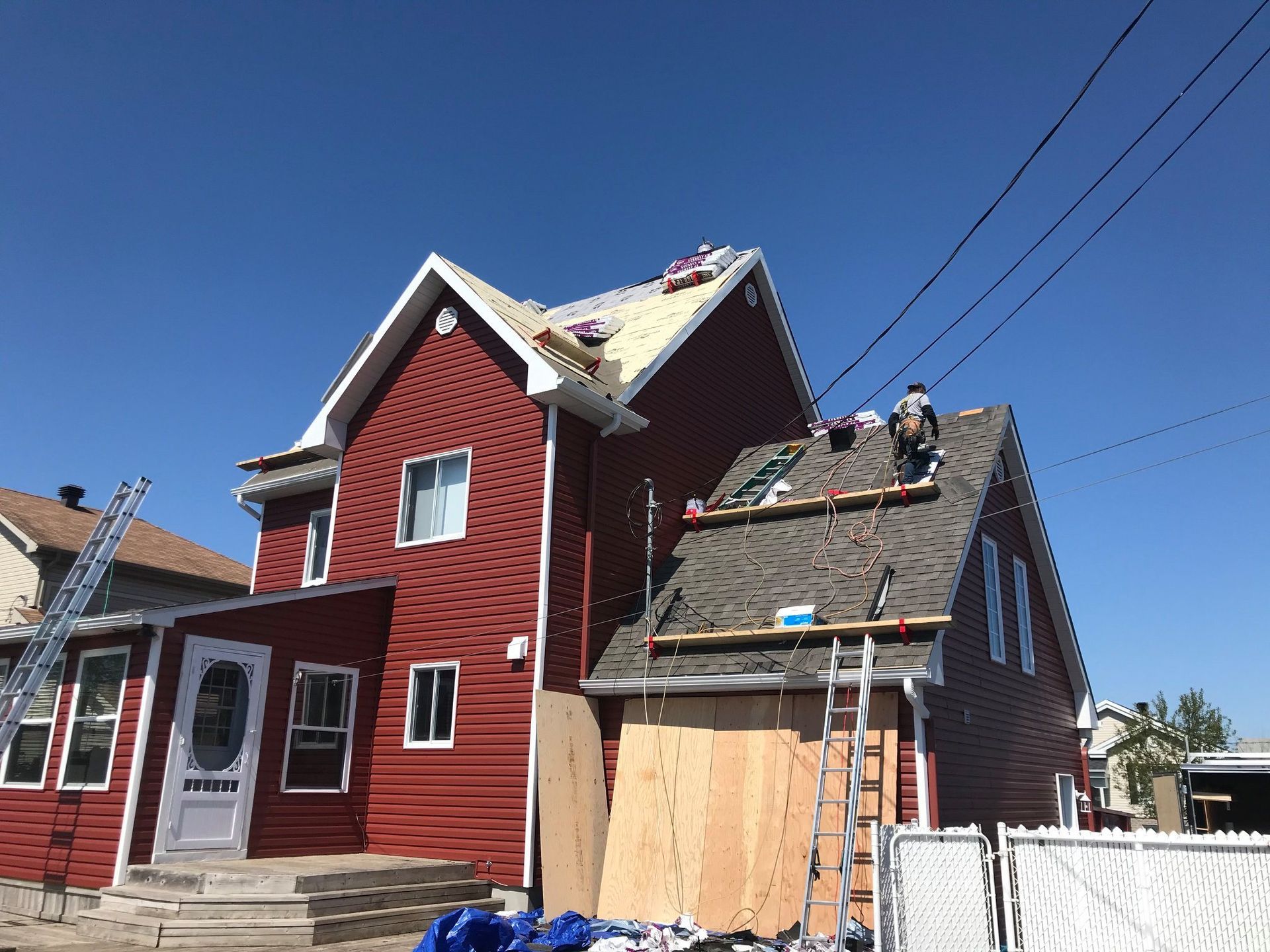 Une maison rouge est en cours de rénovation avec un toit en cours d'installation.