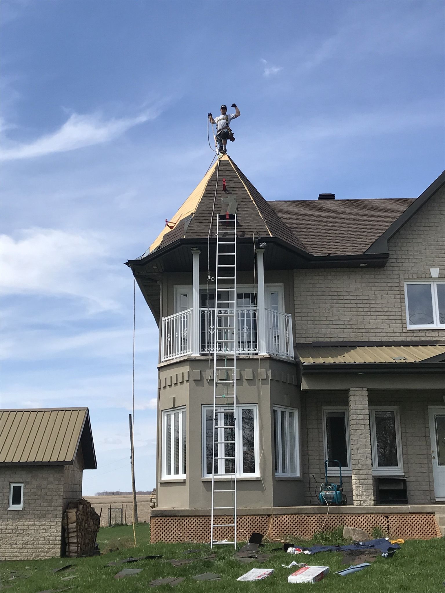 Un homme se tient au sommet d'une maison avec une échelle.