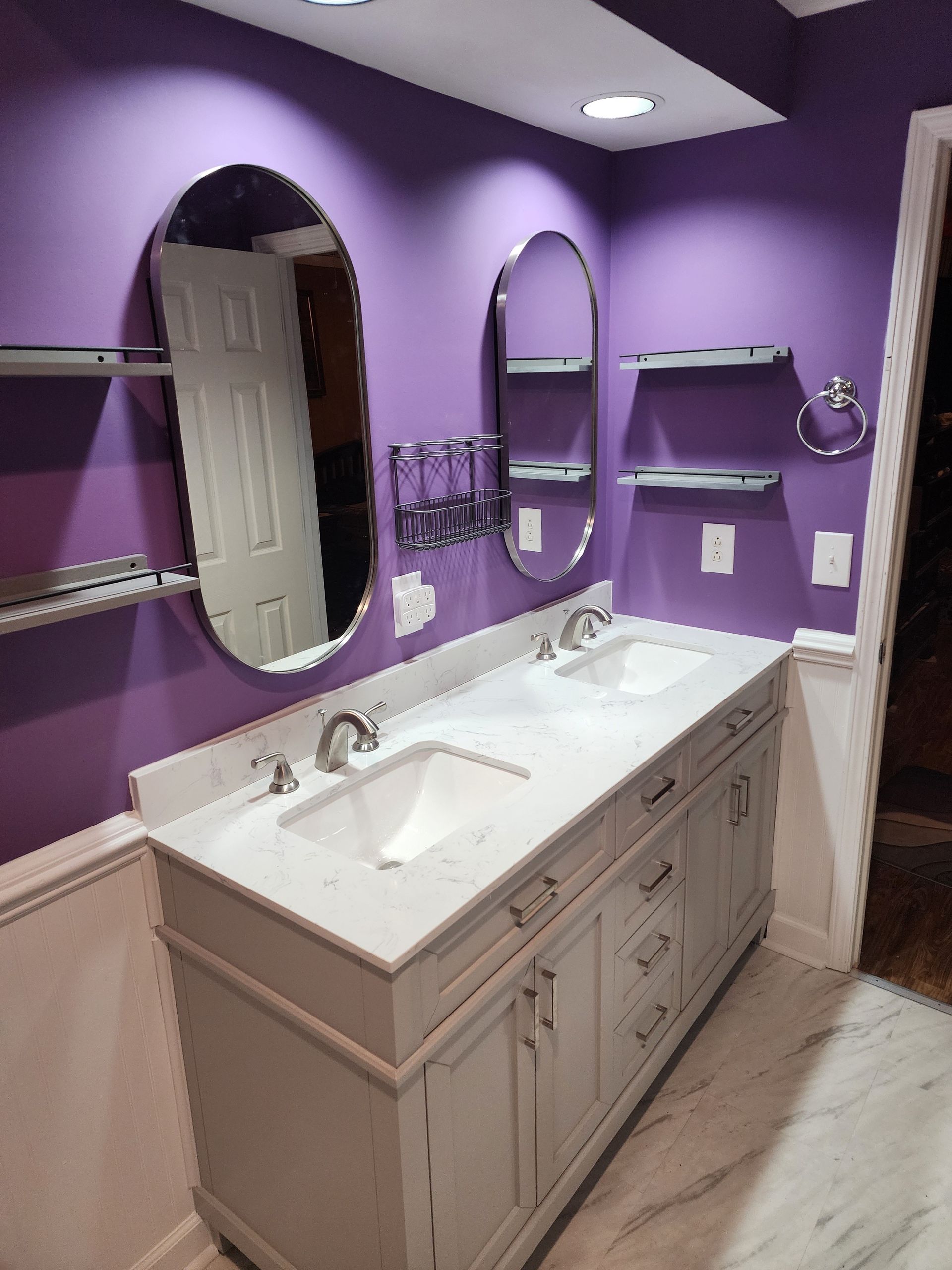 A bathroom with purple walls and a double sink.