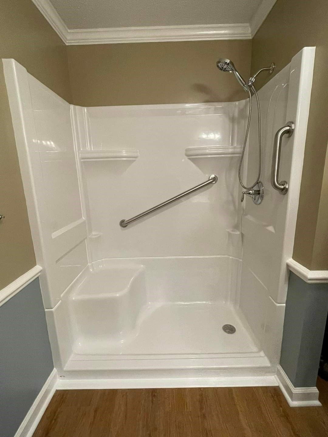A bathroom with a walk in shower with a seat and a hand rail.
