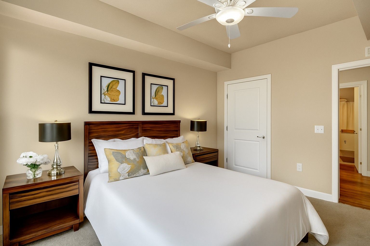 A bedroom with a bed , nightstands , lamps and a ceiling fan.