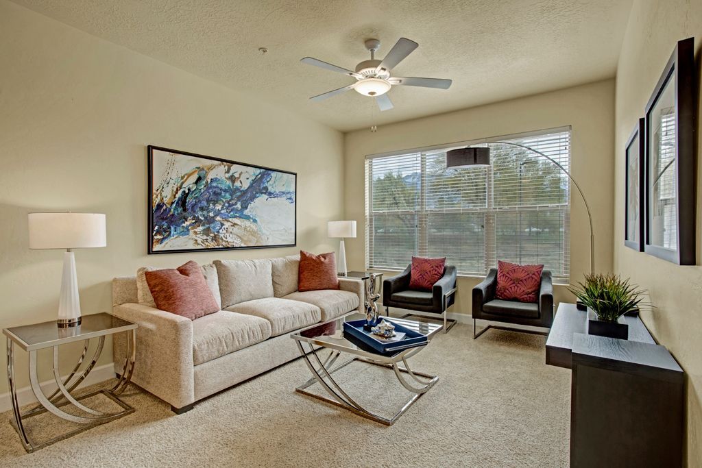A living room with a couch , chairs , a coffee table and a ceiling fan.