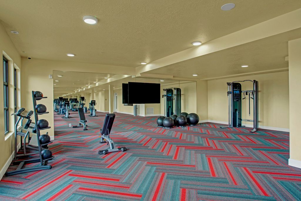 A large gym with a lot of equipment and a flat screen tv.