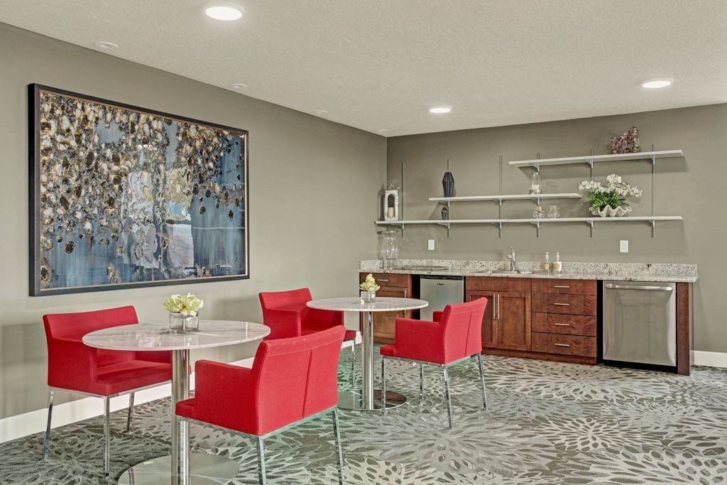A room with tables and chairs and a large painting on the wall.
