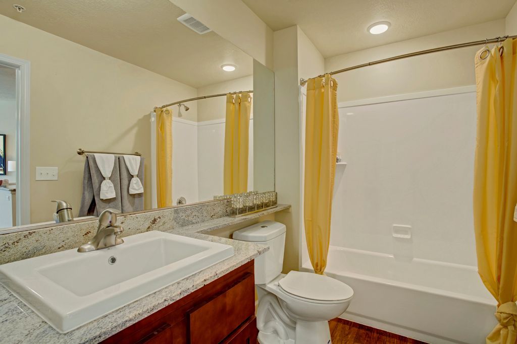 A bathroom with a sink , toilet , tub and mirror.