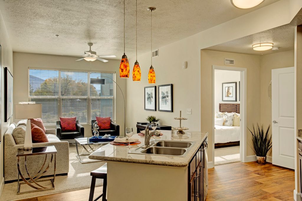 A living room and kitchen in a house with a ceiling fan