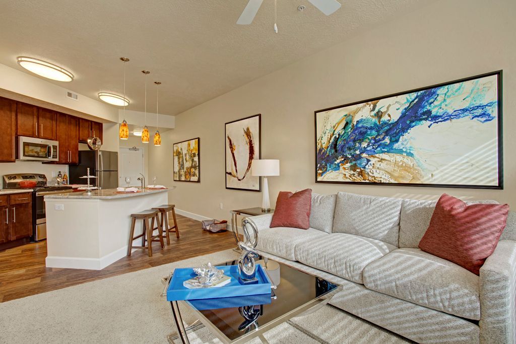 A living room with a couch , coffee table , and a painting on the wall.