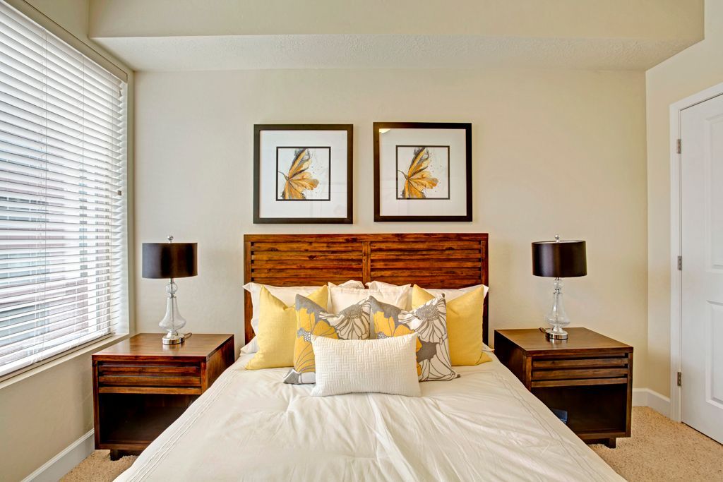 A bedroom with a bed , two nightstands , two lamps and two pictures on the wall.