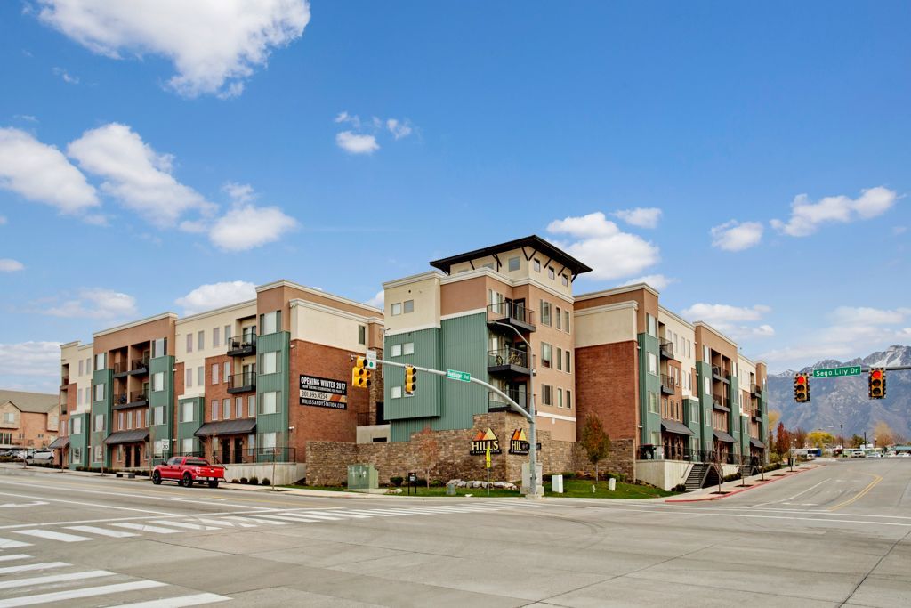 A large apartment building is sitting on the corner of a city street.