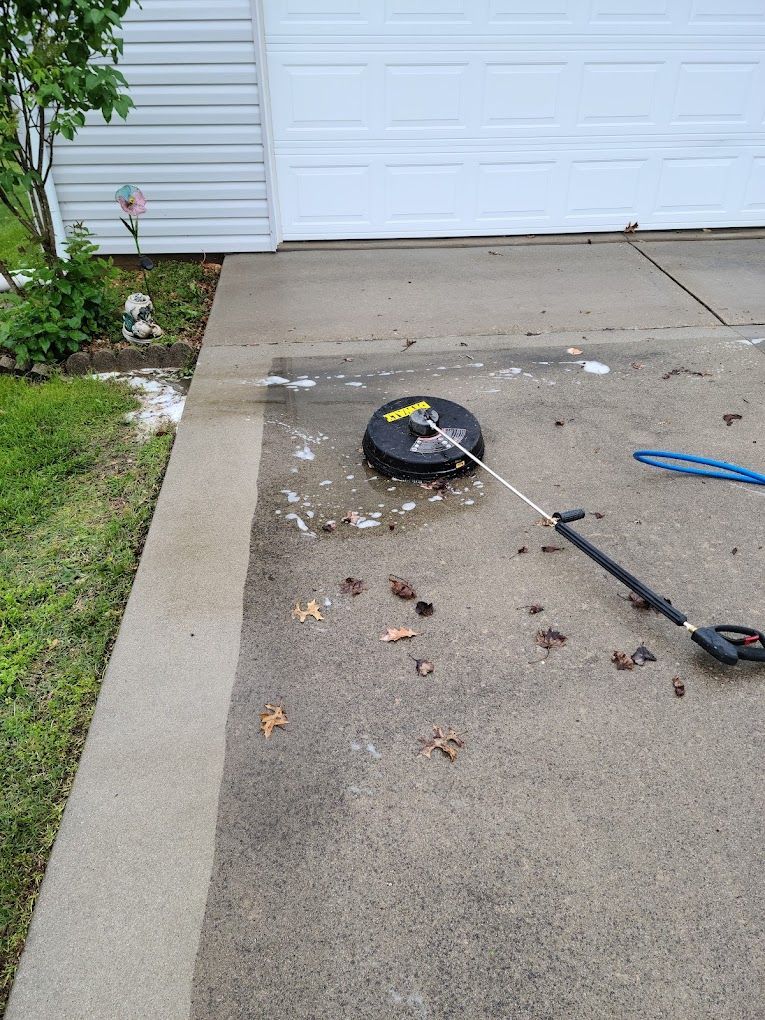 A pressure washer is sitting on a concrete driveway next to a garage door.