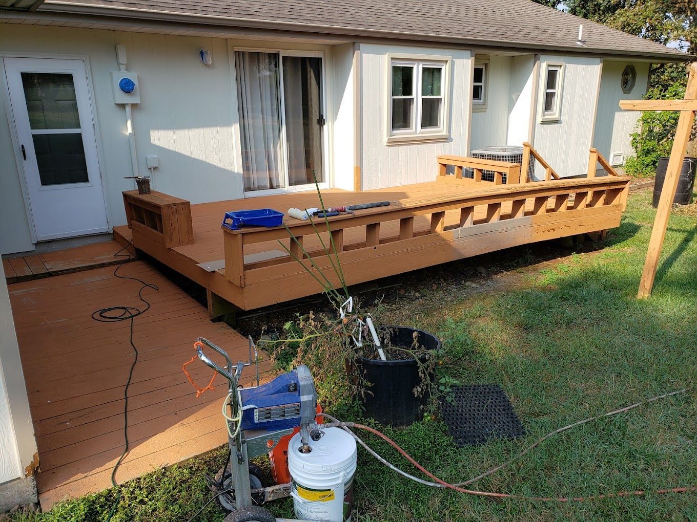 A wooden deck is being painted in front of a house.