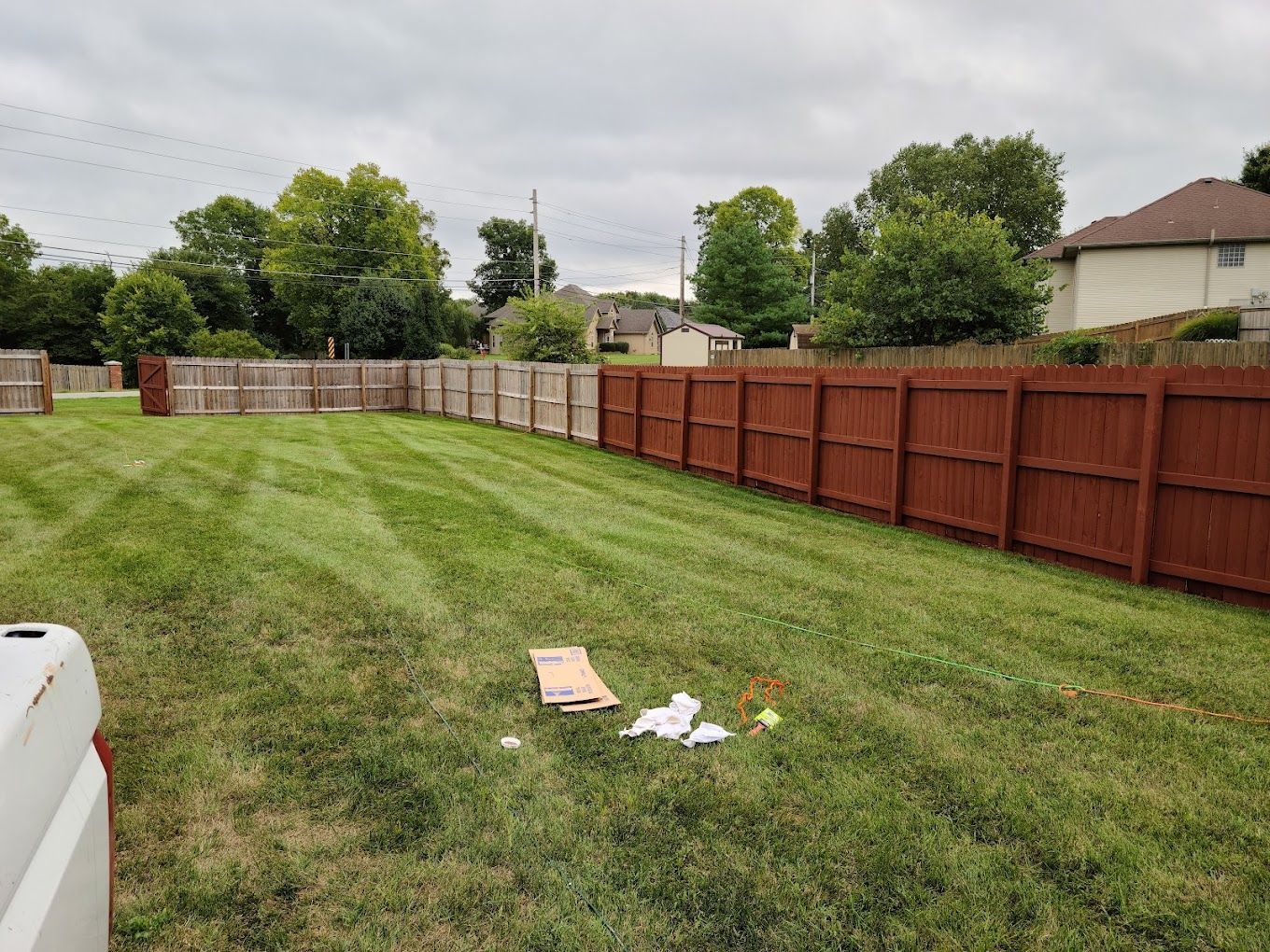 A red wooden fence surrounds a lush green yard.