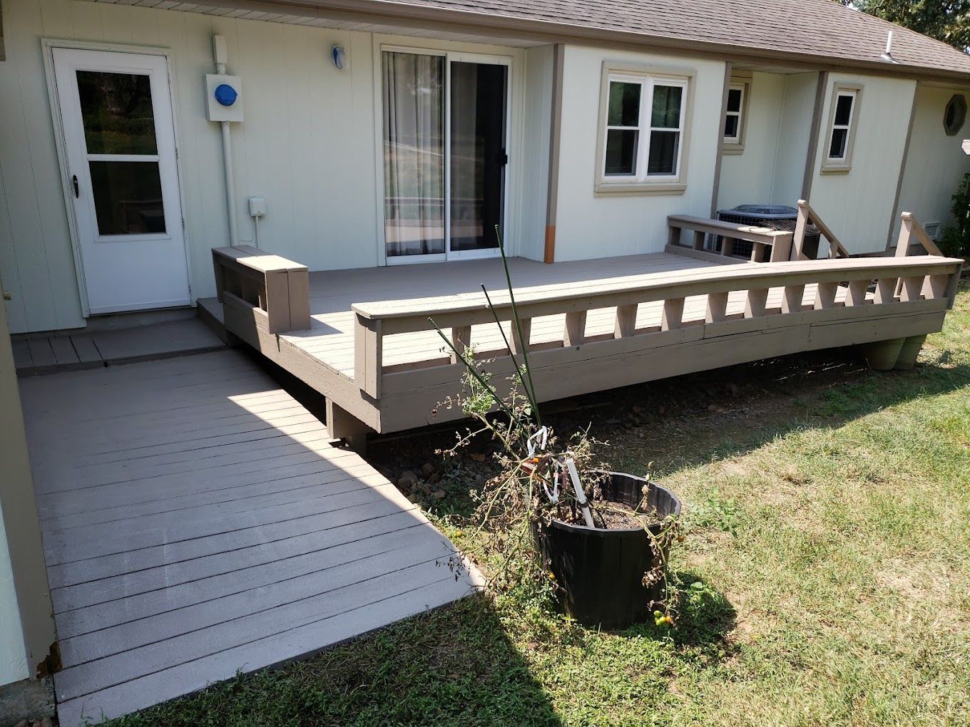 A house with a deck and a potted plant in front of it