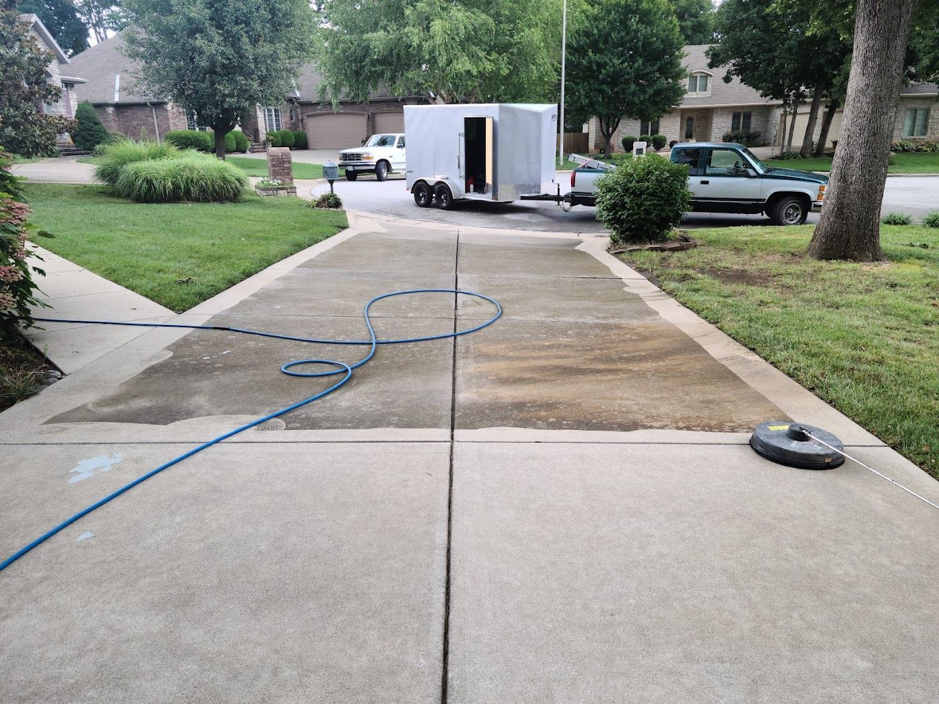A truck is parked on the side of a driveway next to a trailer.