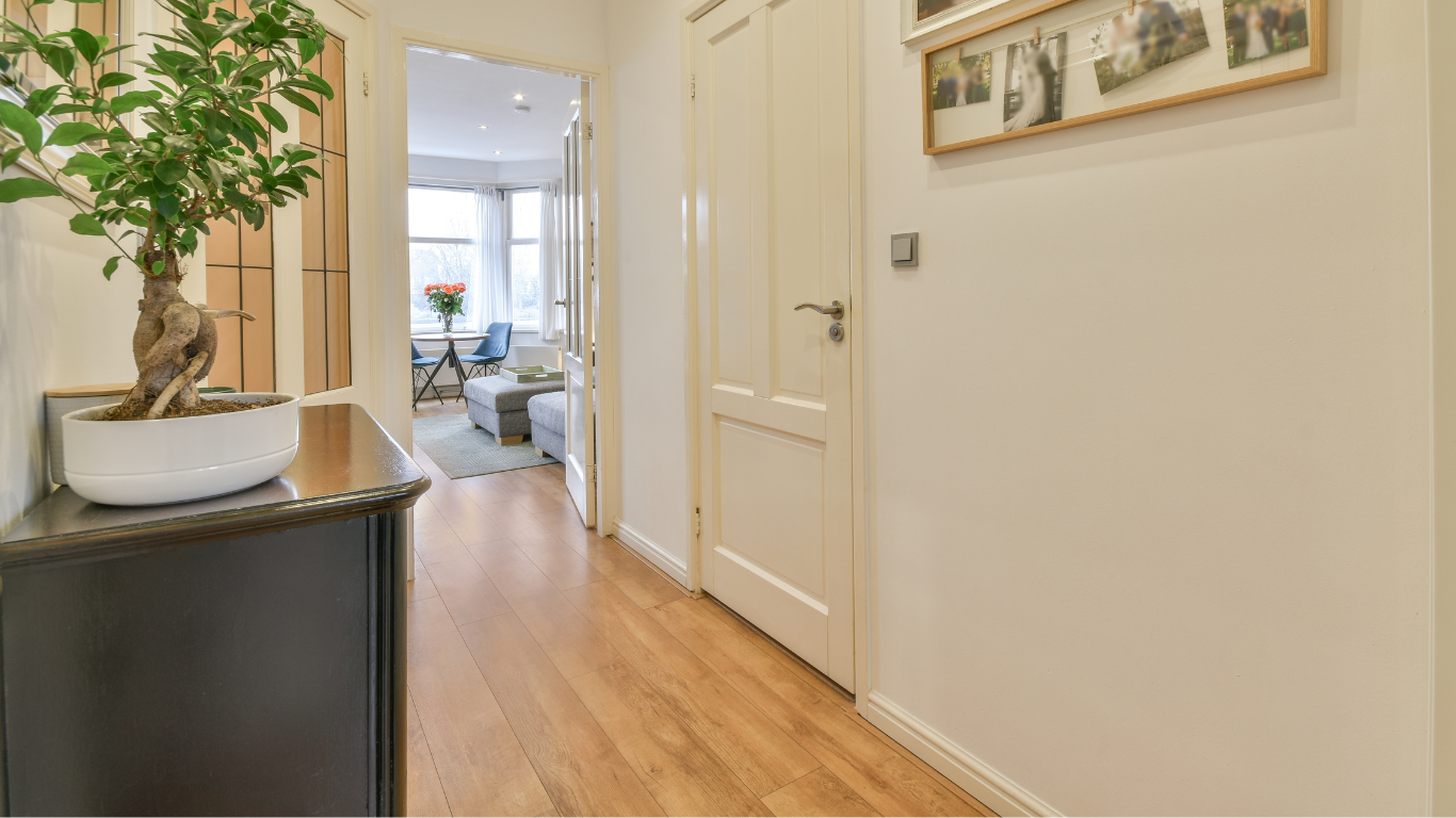 A long hallway with hardwood floors and a plant on a table.