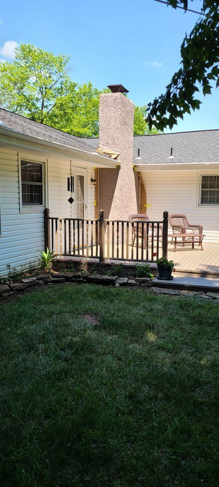A white house with a brick chimney and a patio.