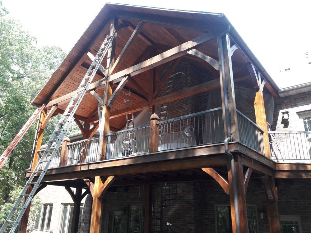 A large wooden house with a screened in porch and a ladder.