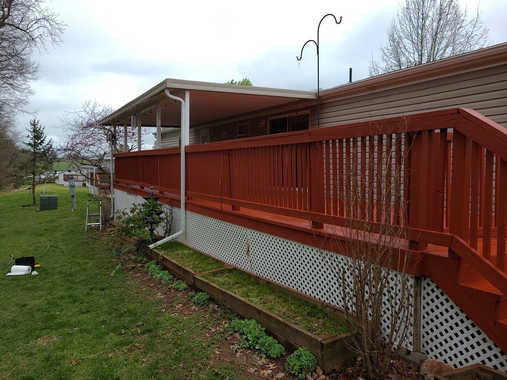 A screened in porch with a wooden deck and a wrought iron railing.